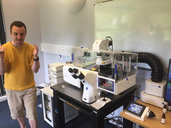Person standing next to a confocal laser microscope